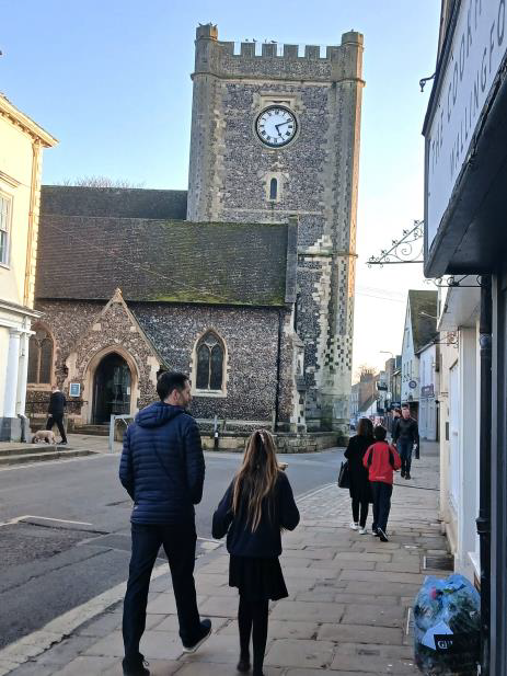 St Mary-le-More Church, Wallingford, Oxfordshire A man and a girl walk along a street towards a clock tower in a historic town.